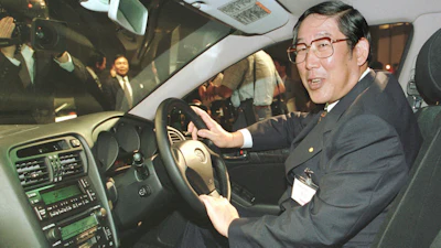 Hiroshi Okuda, then, president of Toyota Motor Corp., smiles as he sits at the steering wheel of the 'Aristo,' Toyota's remodeled sports sedan during a press conference at a Tokyo hotel, Aug. 27, 1997.