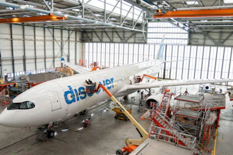 Flydubai aircraft undergoing maintenance in industrial hangar with orange support equipment and scaffolding