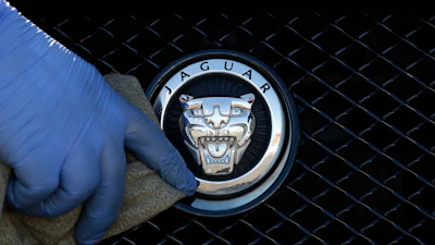 A worker polishes a Jaguar logo on a car at a Jaguar dealer in London, Wednesday Sept. 28, 2016.
