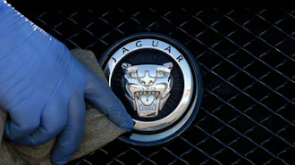 A worker polishes a Jaguar logo on a car at a Jaguar dealer in London, Wednesday Sept. 28, 2016.