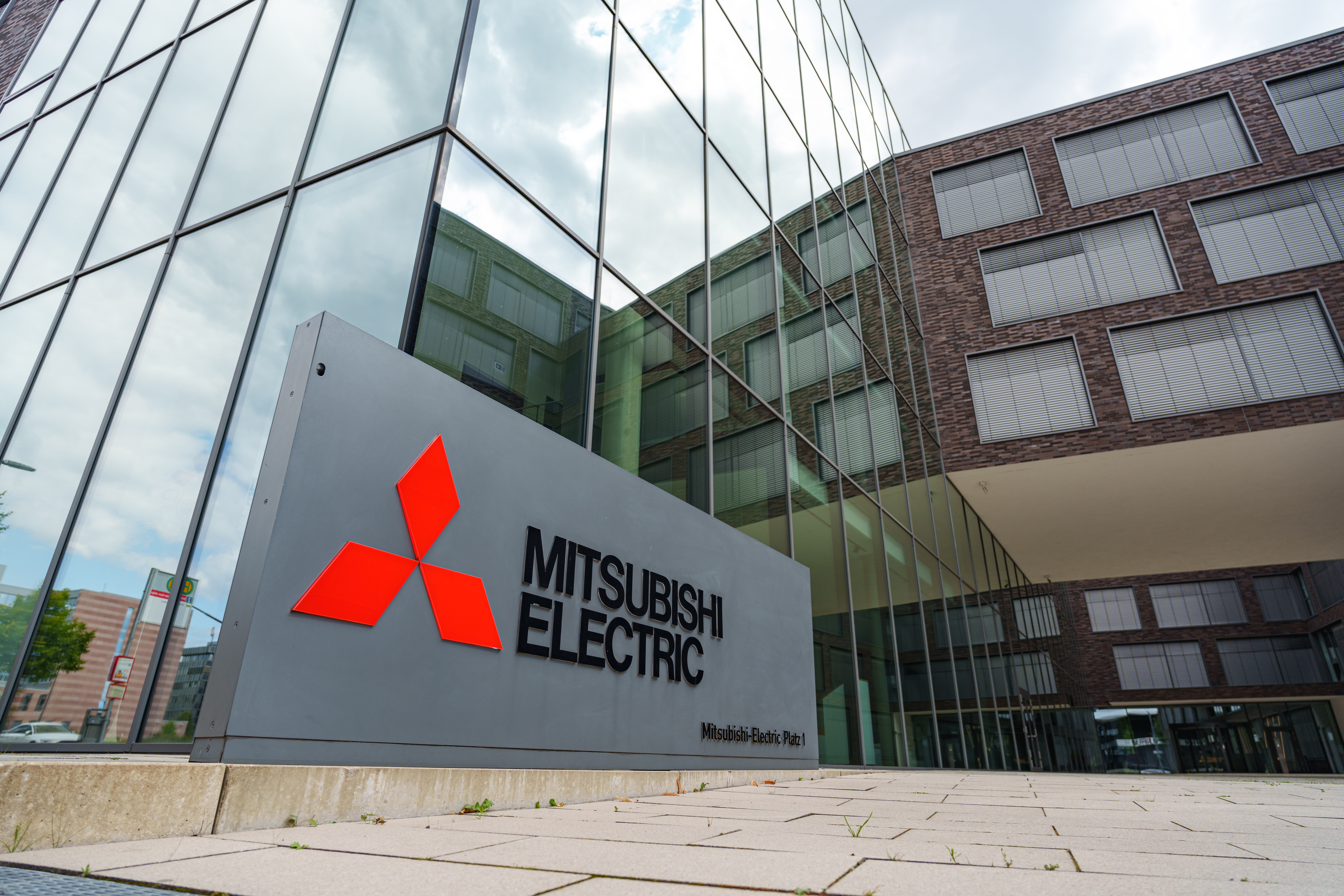 Mitsubishi Electric logo on gray exterior building sign at corporate headquarters entrance