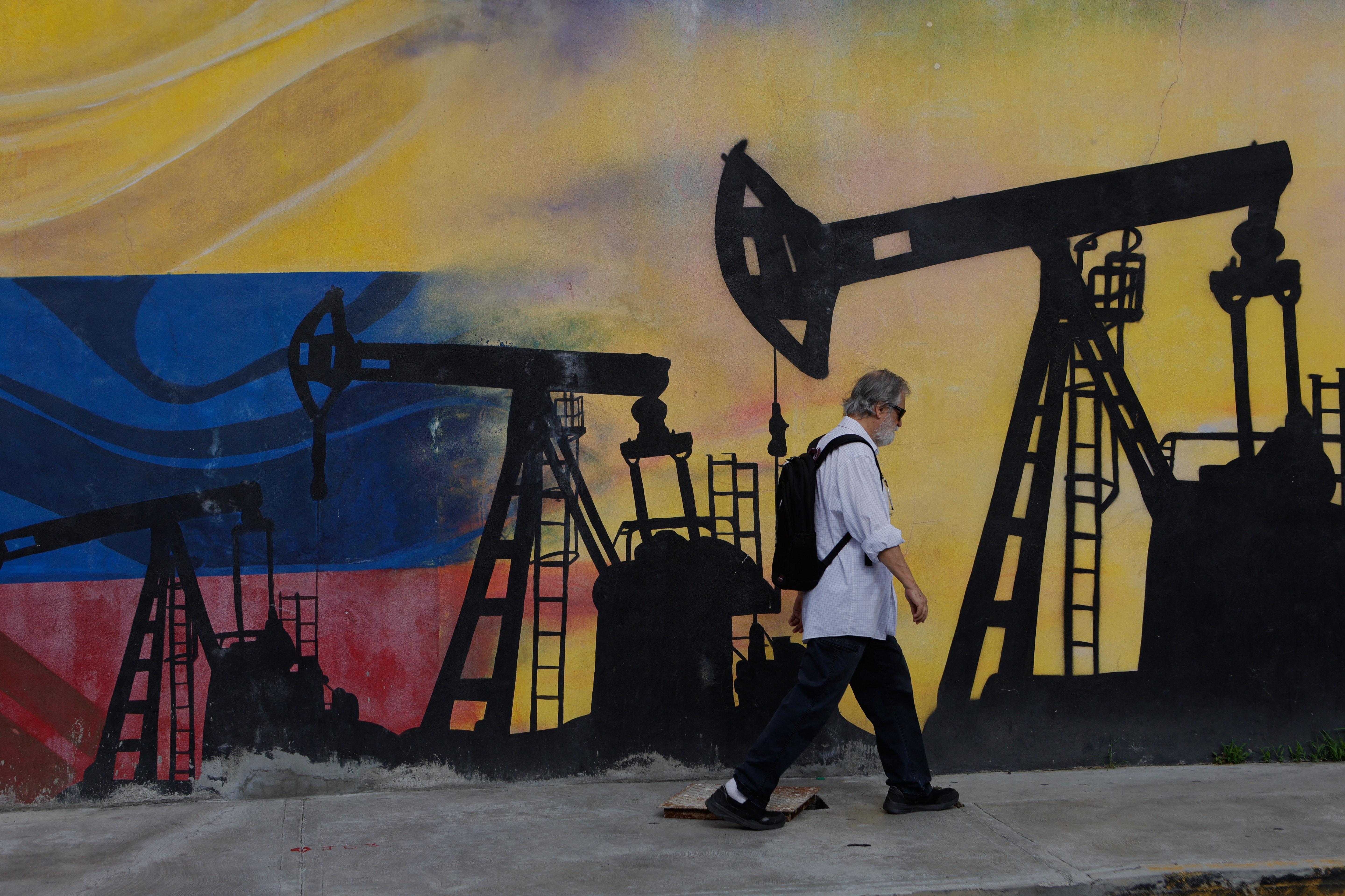 A pedestrian walks past a mural featuring oil wells in Caracas, Venezuela, Saturday, Aug 29, 2026, a day after President Donald Trump announced a deal giving the United States a stake in Venezuela’s oil reserves.