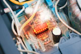 Close-up of circuit board interior with red LED component, resistors, and white wiring visible