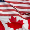 United States and Canadian flags overlapping, showing red and white stripes with stars and maple leaf symbols