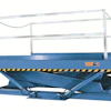 Blue hydraulic scissor lift platform with white safety rails and yellow-black striped bumpers