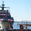 USCGC Maritime Dominance naval vessel at commissioning ceremony with officials and American flags at waterfront dock