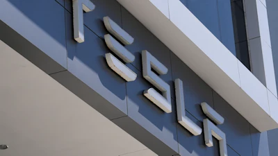 Three-dimensional white lettering mounted on modern blue and white building facade with shadow details