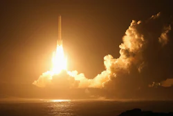 Rocket launching at night with bright engine flames piercing through golden clouds over the ocean