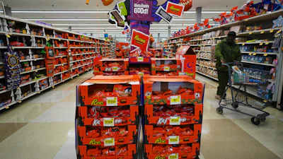 Halloween candy display in retail store featuring Reese's, Kit Kat, and Hershey's products with orange and purple promotional signage.
