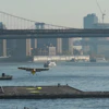 Seaplane landing on East River near Manhattan Bridge with NYC skyline in background