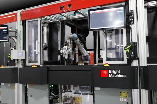 Bright Machines industrial robotic assembly system with red frame, articulated robot arm, and integrated control display