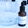 Glycolic acid bottle with dropper in laboratory setting with petri dish and test tubes