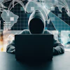 Hooded figure at laptop with global network connections, data analytics charts, and world map overlay representing cybersecurity and digital threats