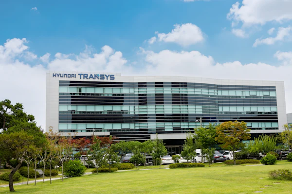 Hyundai Transys modern corporate headquarters building with glass facade and landscaped grounds under blue sky