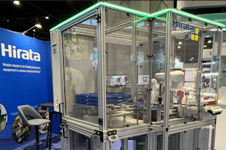 Hirata industrial manufacturing equipment with transparent enclosure and green frame on blue trade show floor