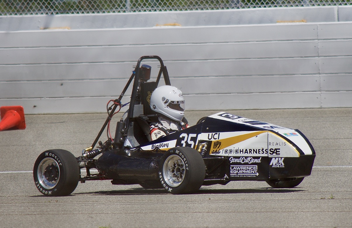 Black and white formula SAE race car with number 35 on concrete track near barrier