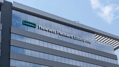 Modern glass and steel office building with company signage on facade under blue sky