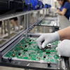 Electronics factory workers assembling and inspecting green circuit boards on an industrial production line