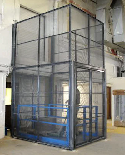 Industrial safety cage with black mesh screening and blue safety railings in warehouse