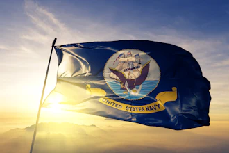 United States Navy flag waving against golden sunset sky with mountains in background