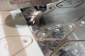 CNC machining workstation with white plastic components and metal parts with protective film during manufacturing process