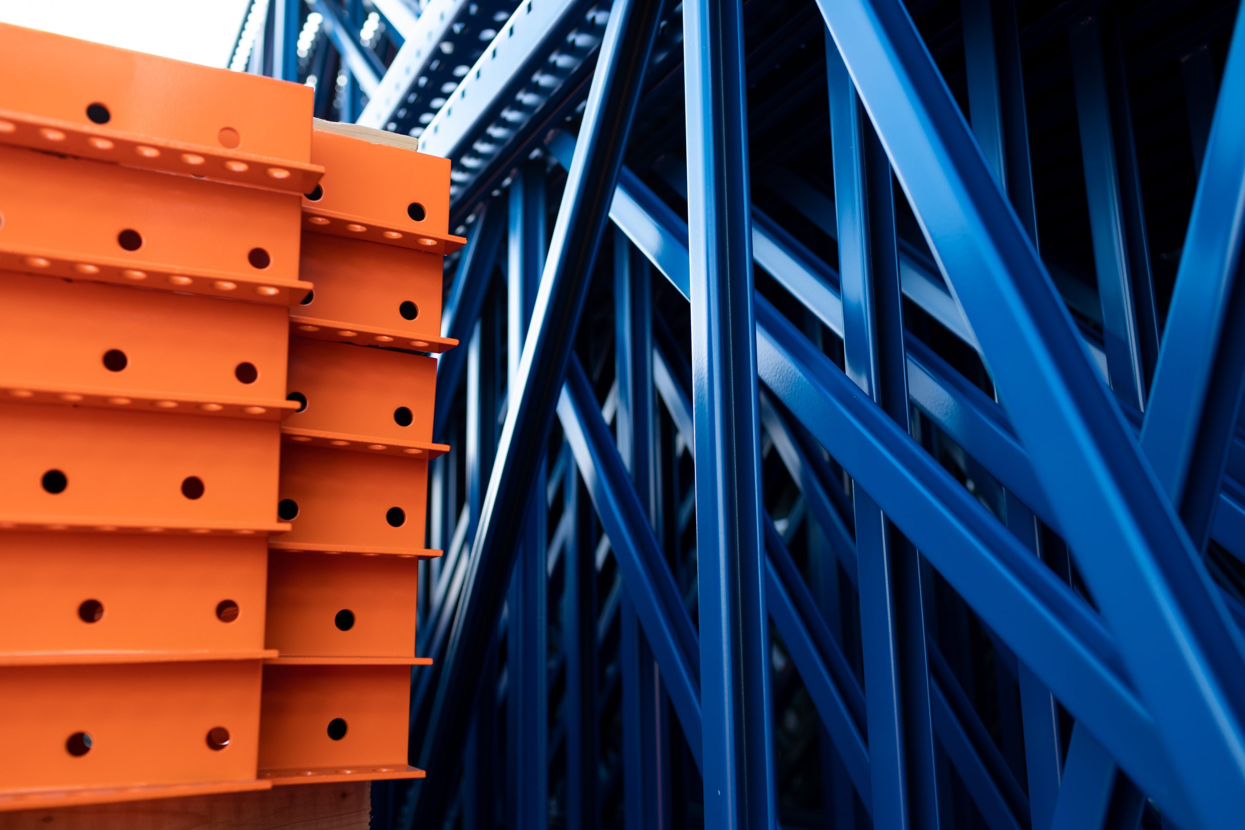 Orange and blue industrial warehouse racking system with metal shelving and structural beams