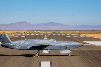 Gray RQ-4 Global Hawk military drone aircraft parked on desert runway with mountains in background