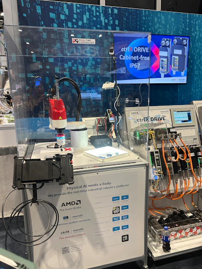 Industrial robotics exhibition booth featuring AMDZ real-time controller, ctrIX DRIVE cabinet-free IP67 system, and Rexroth components with robotic arm demonstration