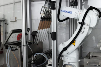 ASKAWA industrial robotic arm with tool changer mounted in manufacturing enclosure