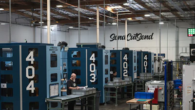 Industrial manufacturing facility with blue CNC machines and Sena CutSend signage on warehouse wall