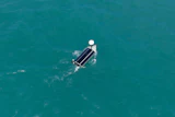 Aerial view of a pontoon boat on clear turquoise water with white canopy