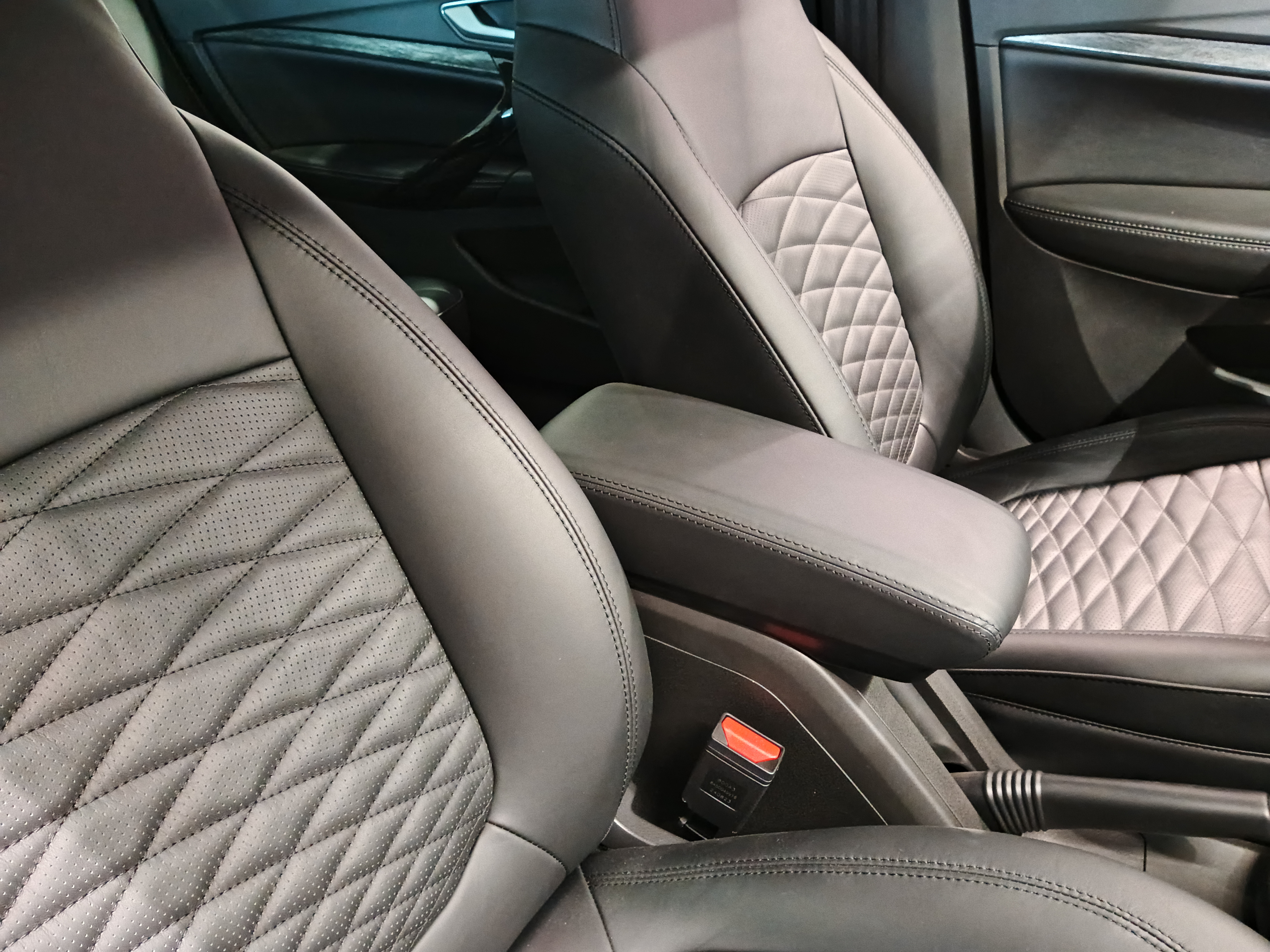Luxury car interior with quilted leather seats in light gray and black tones, center console visible
