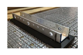 Metal channel track with mounting holes and black base on textured surface