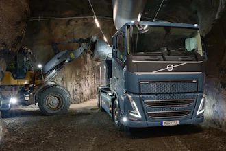 Volvo truck and wheel loader operating in an underground tunnel construction site with bright LED lighting