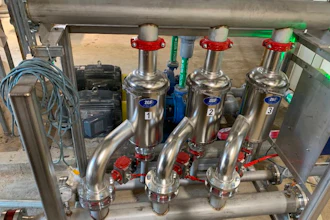 Industrial stainless steel multi-valve manifold system with red handles mounted on frame in workshop